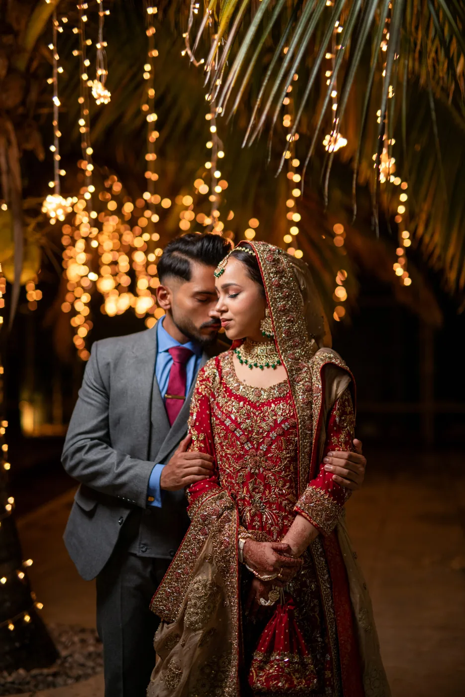 Wedding couple standing under a canopy illuminated by warm fairy lights at night
